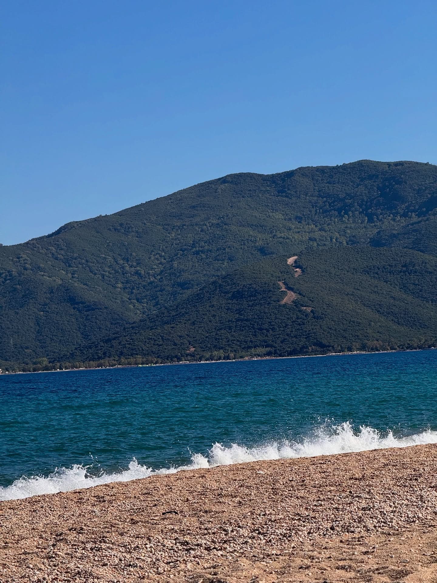 Turquoise Aegean sea, pebble beach and green mountain at Asprovalta