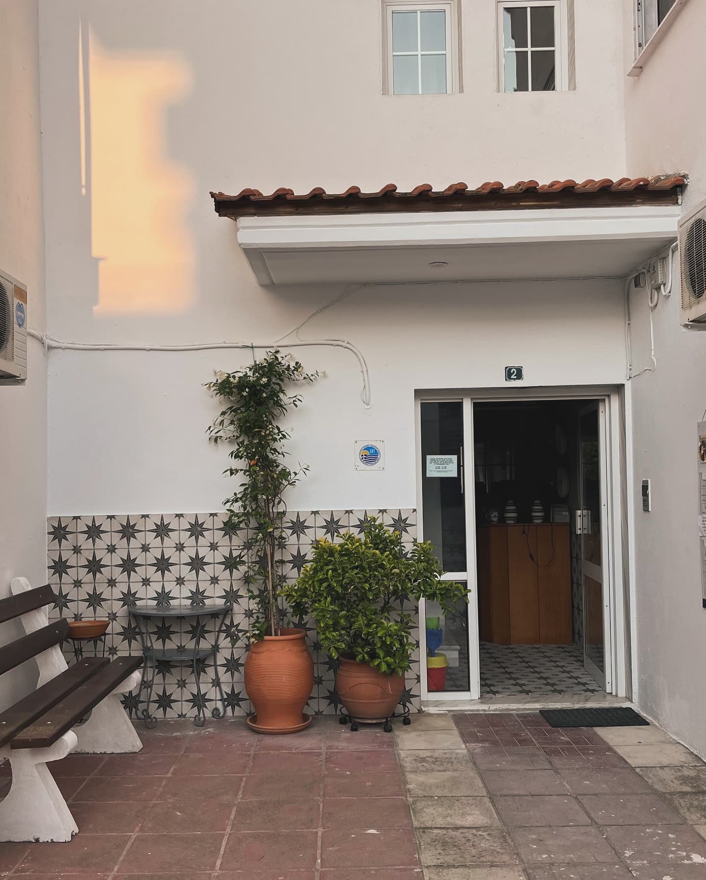 White apartment entrance with terracotta pots and tiled wall
